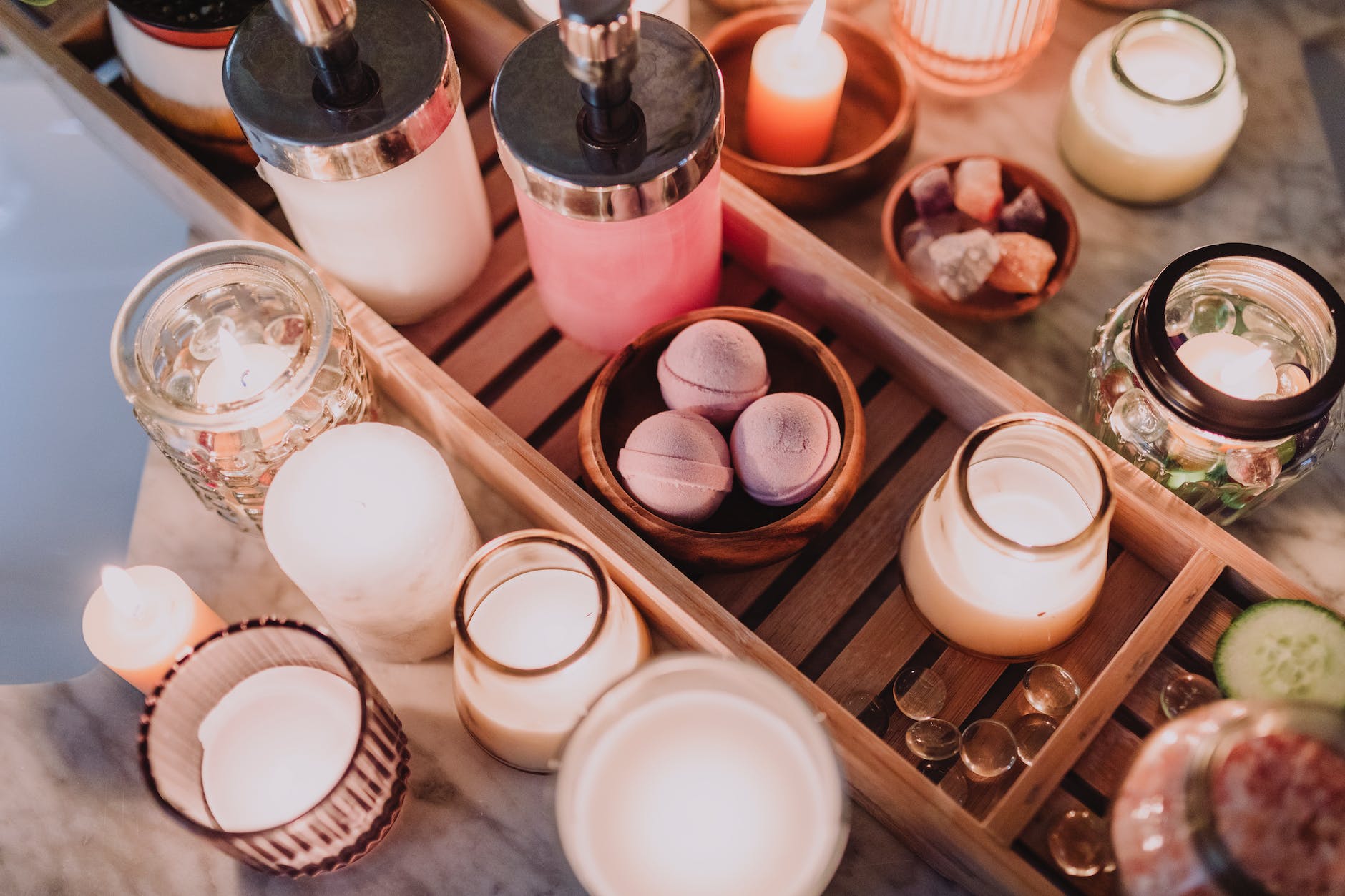 lighted candles in glass jars and containers on a wooden tray